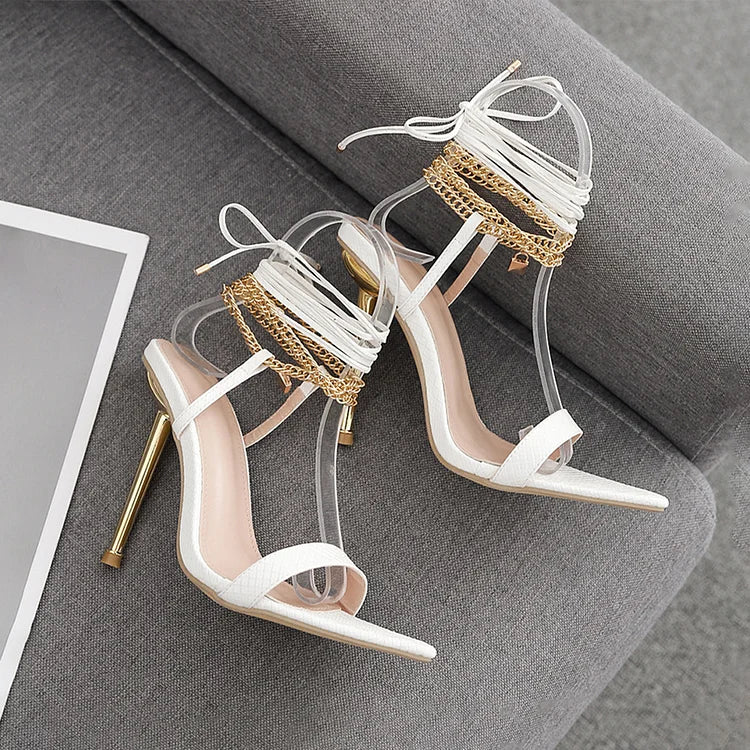 Scarpe con tacco a spillo a punta con lacci incrociati e decorazioni in metallo lucido